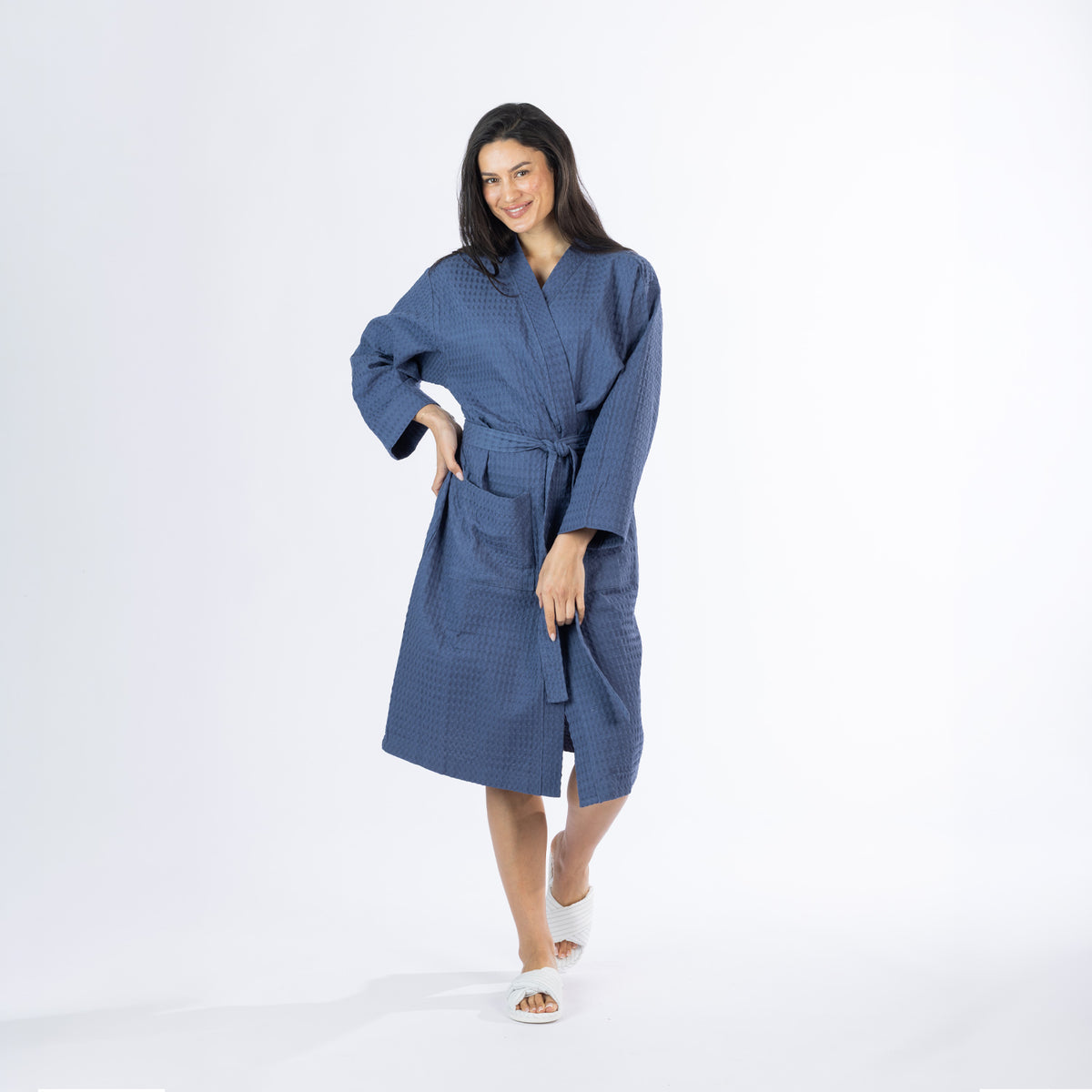Full-length view of a model wearing an indigo Cove Dilys Waffle Bathrobe with long sleeves, front pockets and a matching waist tie belt.