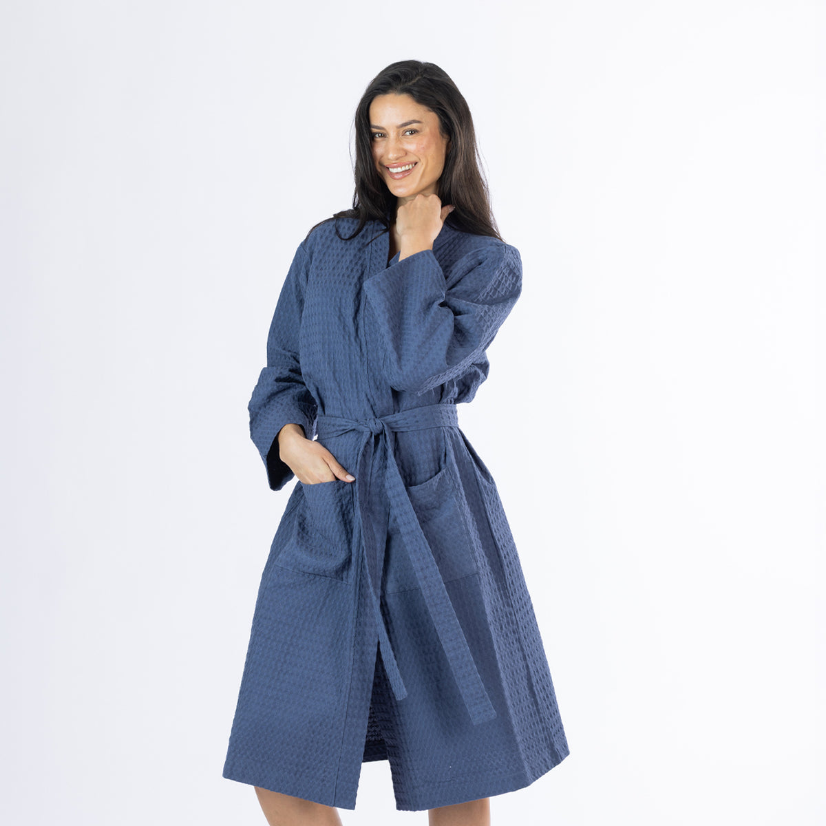 Model posing in an indigo Cove Dilys Waffle Bathrobe featuring a textured waffle pattern, front pockets and matching waist tie belt.