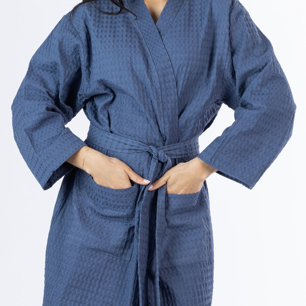 Close-up of an indigo Cove Dilys Waffle Bathrobe showing the textured waffle fabric, front pockets and matching waist tie belt.