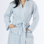 Close-up of the pale blue textured stripe robe showing the lightweight crinkled texture, wrap front, waist tie and two patch pockets.