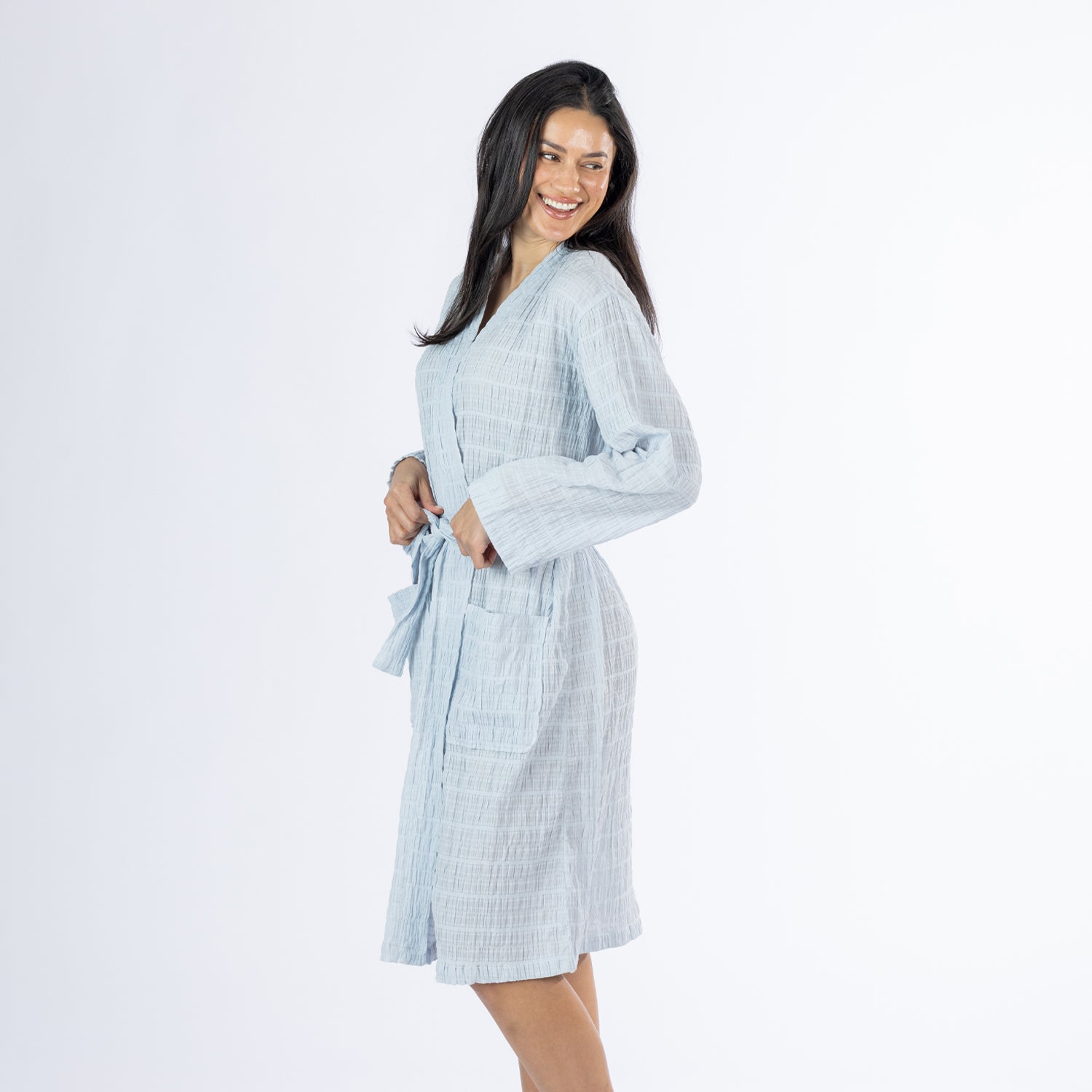 Three-quarter side view of a model wearing the pale blue textured stripe robe, highlighting the relaxed fit, long sleeves and knee-length design.