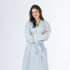 Mid-length front view of a model wearing the pale blue textured stripe robe with crossed arms, showing the textured fabric, wrap neckline and waist tie.