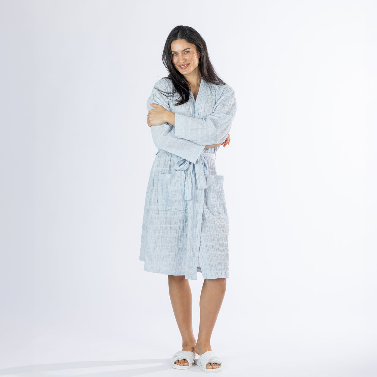 Full-length front view of a model wearing the pale blue textured stripe robe with crossed arms, tie waist and front patch pockets.