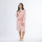 Full-length front view of a model wearing the pink textured stripe robe with the tie belt fastened and one hand raised near the neckline.
