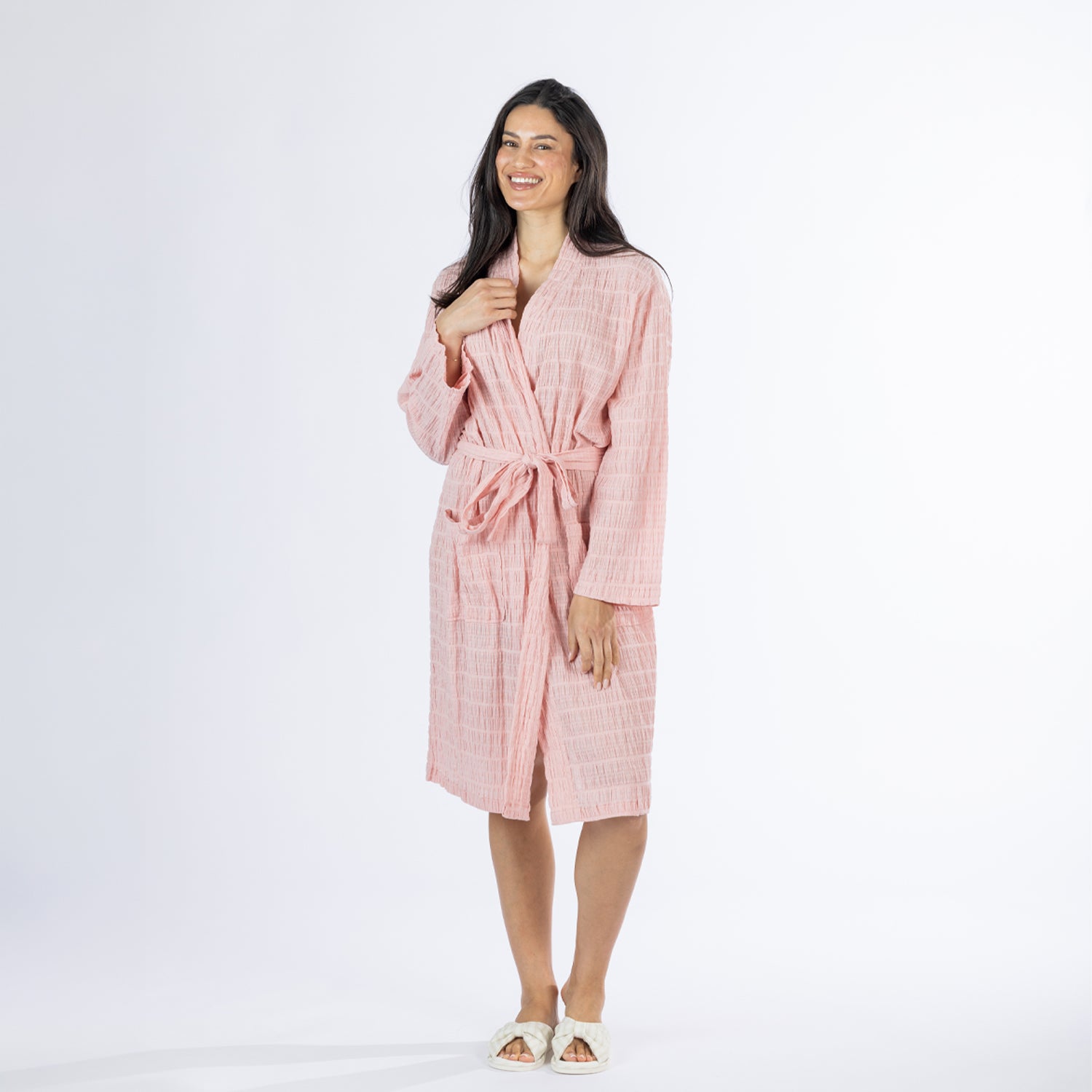 Full-length front view of a model wearing the pink textured stripe robe with the tie belt fastened and one hand raised near the neckline.