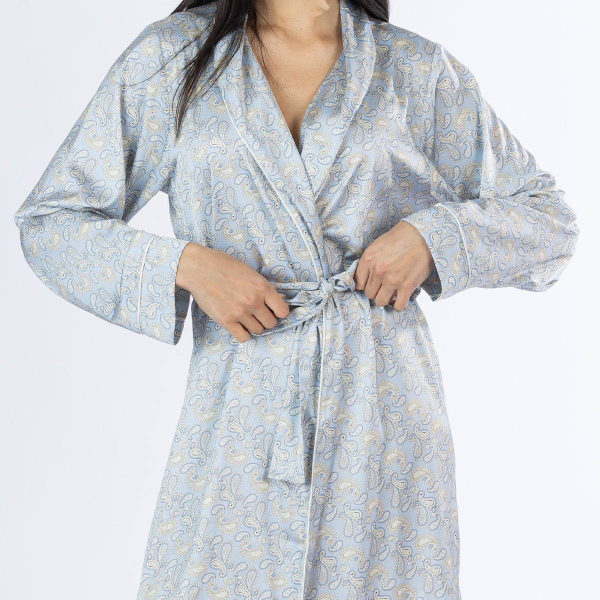 Close-up of the Amparo Cassie Satin Print Bathrobe in Denim, highlighting the intricate paisley pattern, shawl collar, white piping and matching fabric waist tie.
