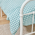 close up of the bb&b Kids Gingham seafoam duvet cover set styled on a white metal bed.