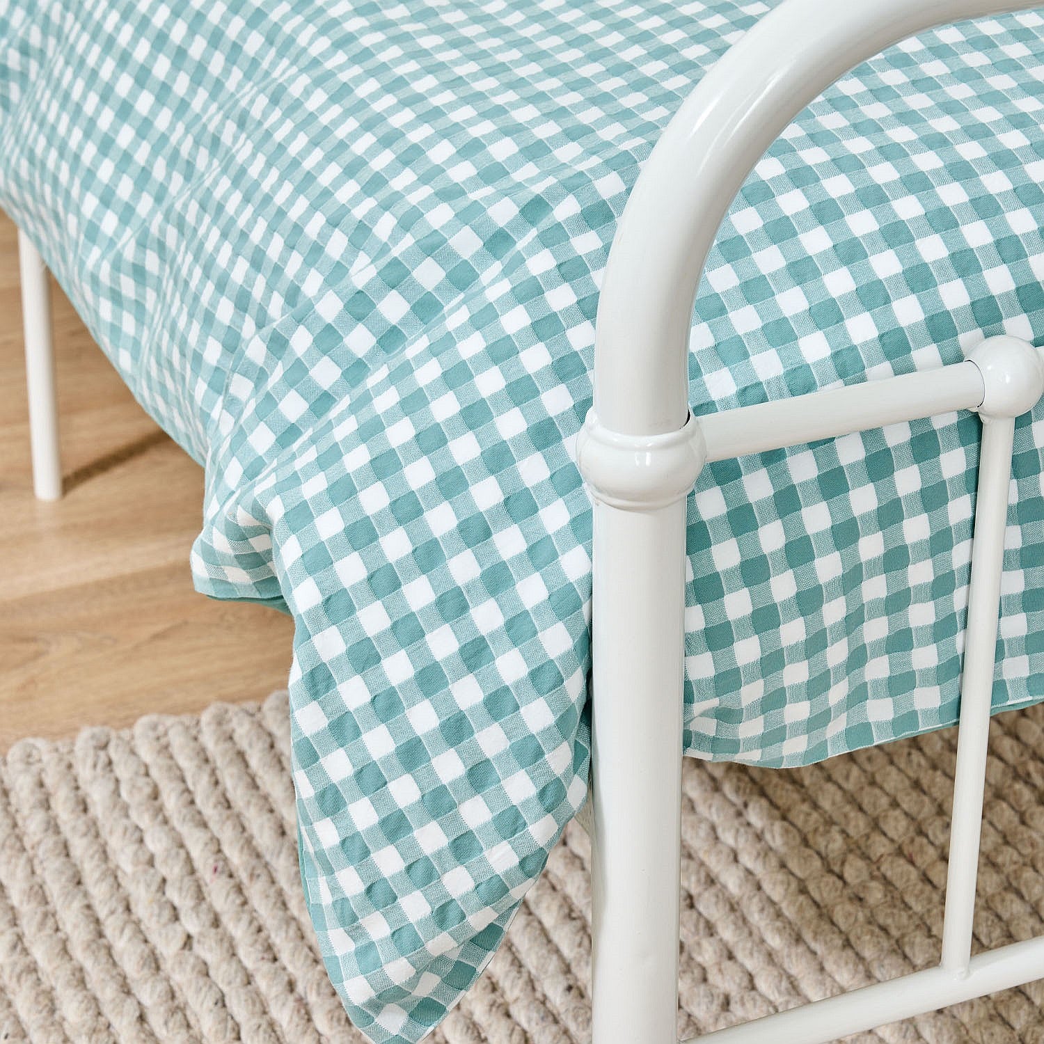 close up of the bb&b Kids Gingham seafoam duvet cover set styled on a white metal bed.