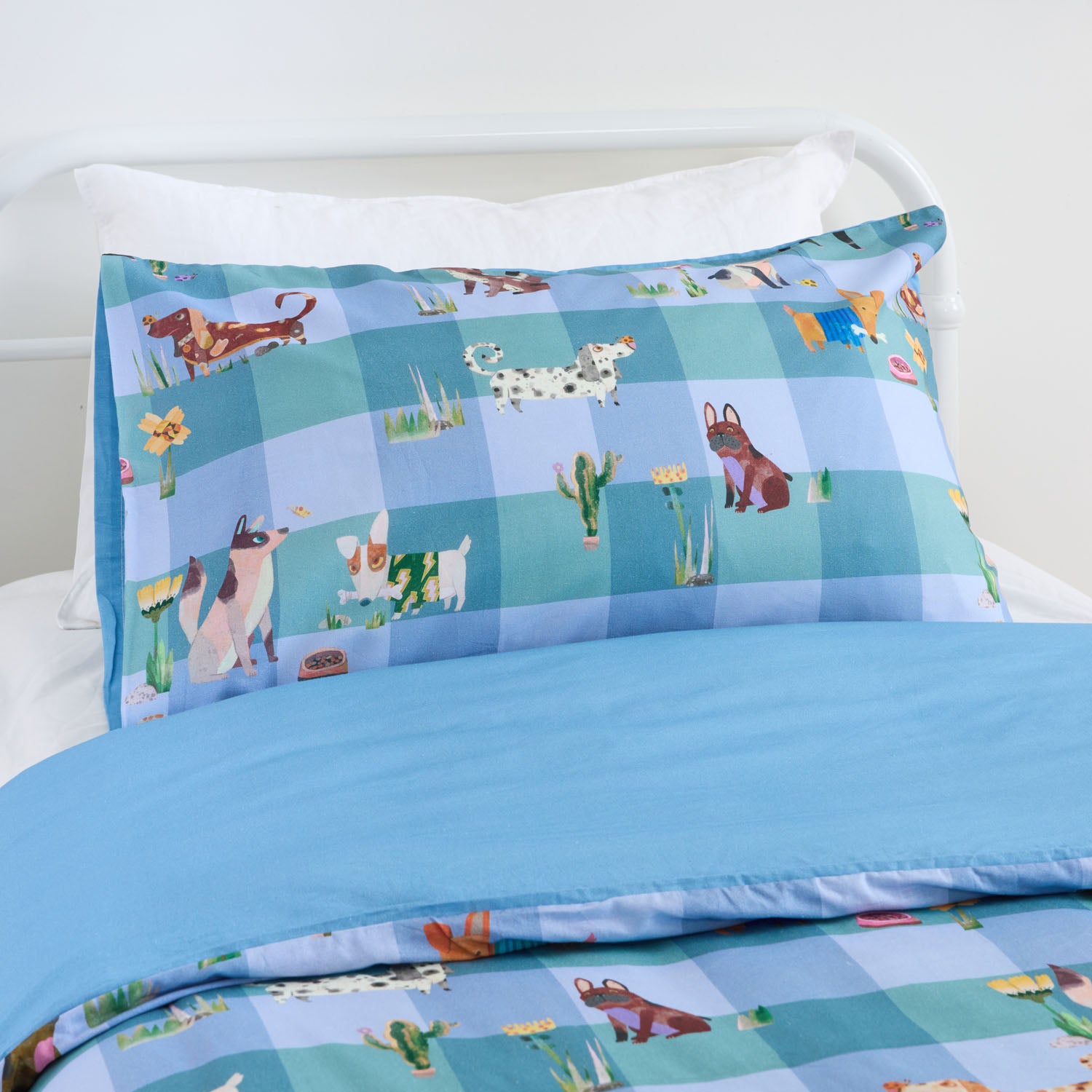 Kids blue animal print duvet cover set styled on a white metal bed in a neutral bedroom.