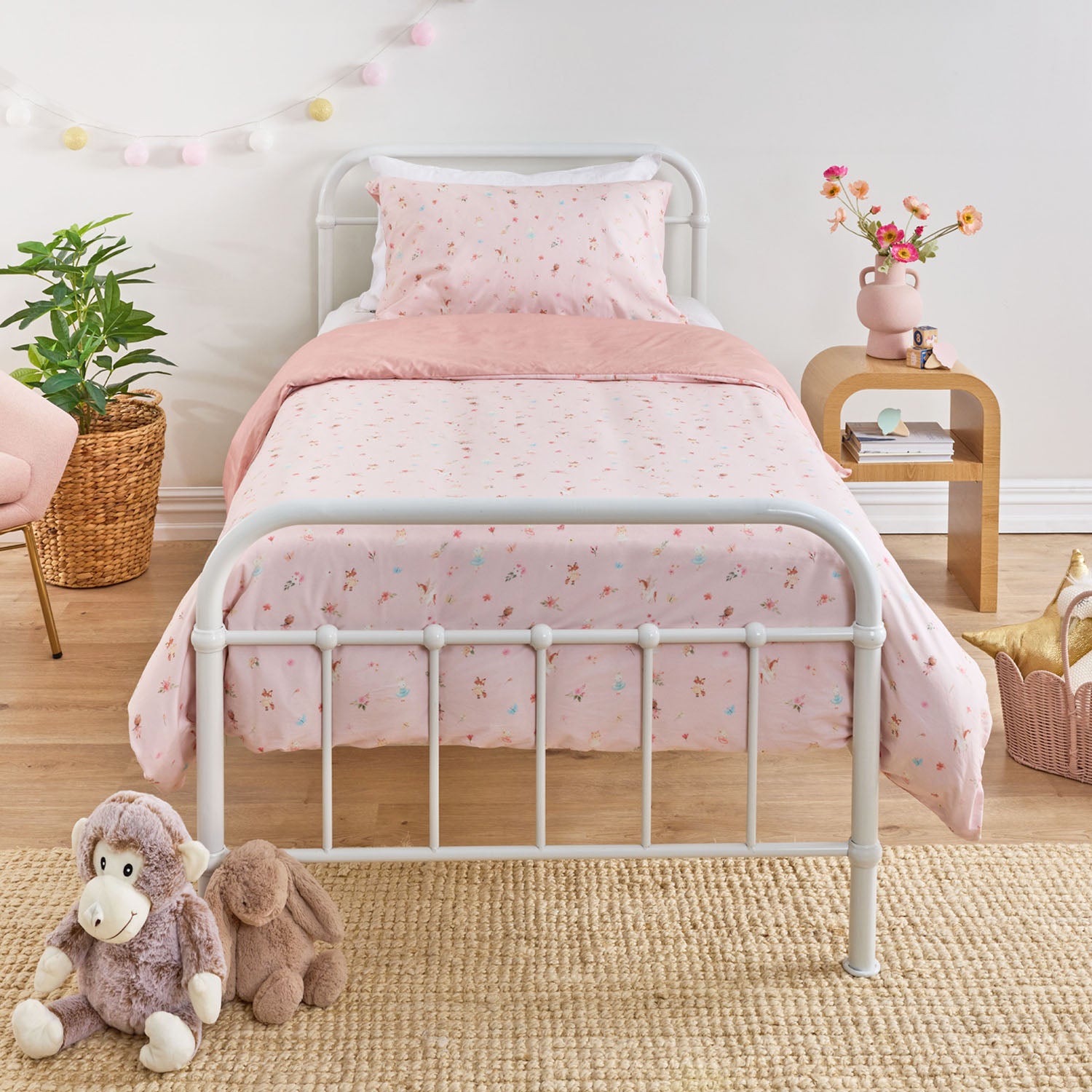 Kids floral print duvet cover set with small scattered flowers and leaves styled on a white metal bed in a neutral bedroom.