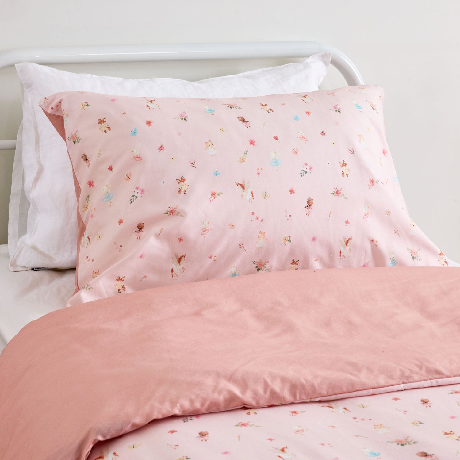 Kids floral print duvet cover set pillowcase with small scattered flowers and leaves styled on a white metal bed in a neutral bedroom.