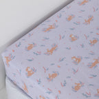 Purple fitted sheet with bunnies and flowers on a white mattress.