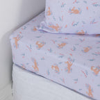 Purple fitted sheet with bunnies and flowers on a white mattress with a matching pillowcase