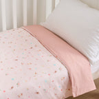 close up of baby cot styled with a pale pink in a soft neutral nursery room with a white pillow 
