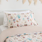 Kids carnival patterned duvet cover set styled on a white metal bed in a neutral bedroom.