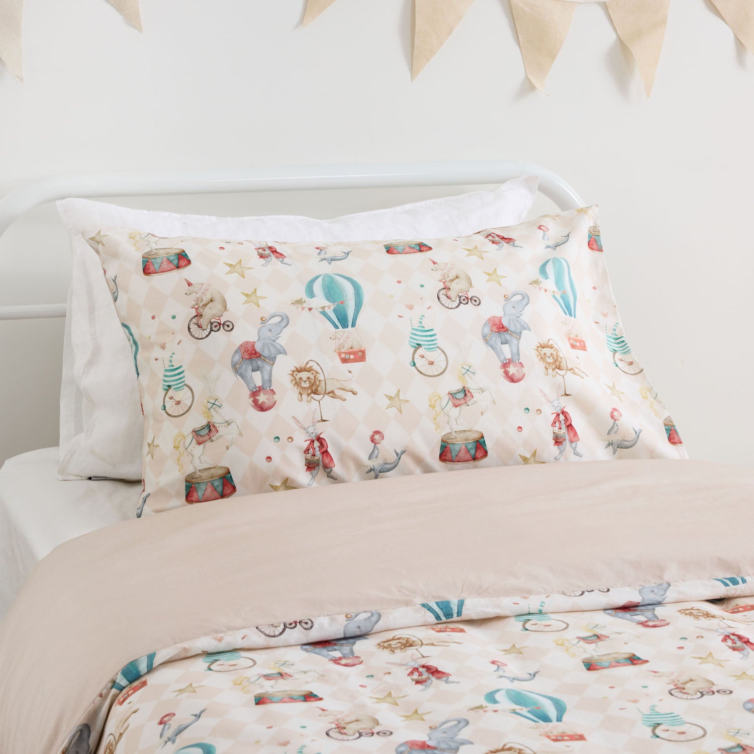 Kids carnival patterned duvet cover set styled on a white metal bed in a neutral bedroom.