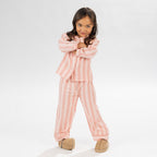 Child wearing pink striped flannelette pyjamas on a white background.