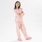 Child wearing pink striped flannelette pyjamas on a white background.
