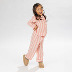 Child wearing pink striped flannelette pyjamas on a white background.
