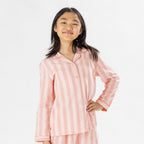 Child wearing pink striped flannelette pyjamas on a white background.