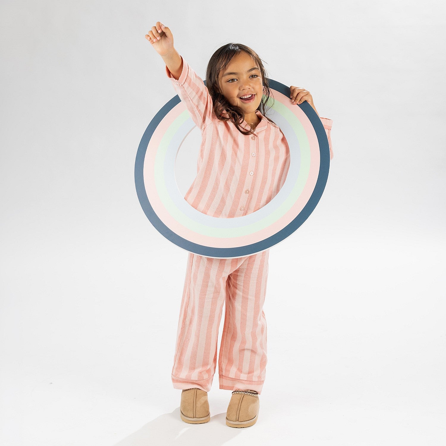 Child wearing pink striped flannelette pyjamas on a white background.