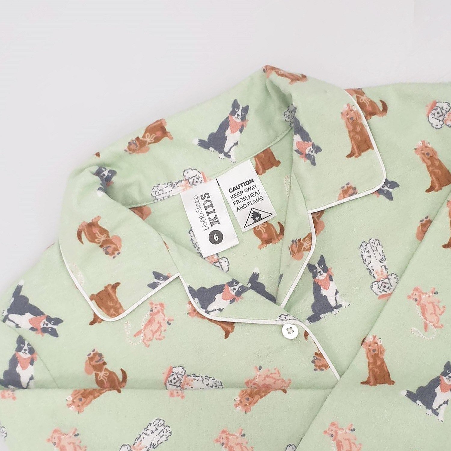 Child wearing bb&b Sleep Kids Dog flannelette pyjama set up close showing the tags