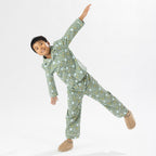 Child wearing green soccer print pyjamas standing on a white background.