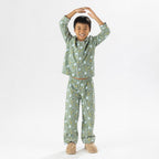 Child wearing green soccer print pyjamas standing on a white background.