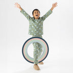 Child wearing green soccer print pyjamas standing on a white background.