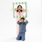 Two kids wear stripe Flannelette pyjamas, ones navy and ones in pink. 