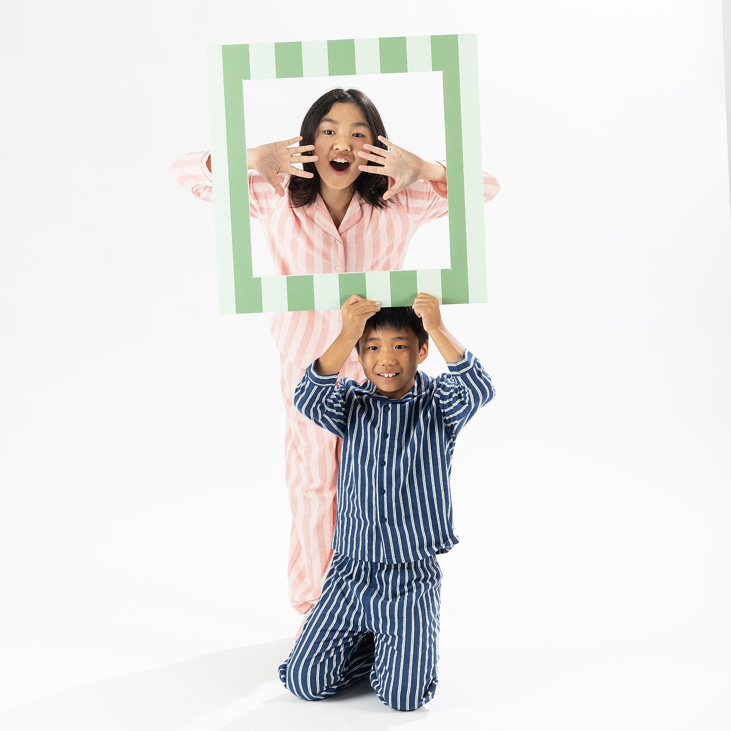 Two kids wear stripe Flannelette pyjamas, ones navy and ones in pink. 