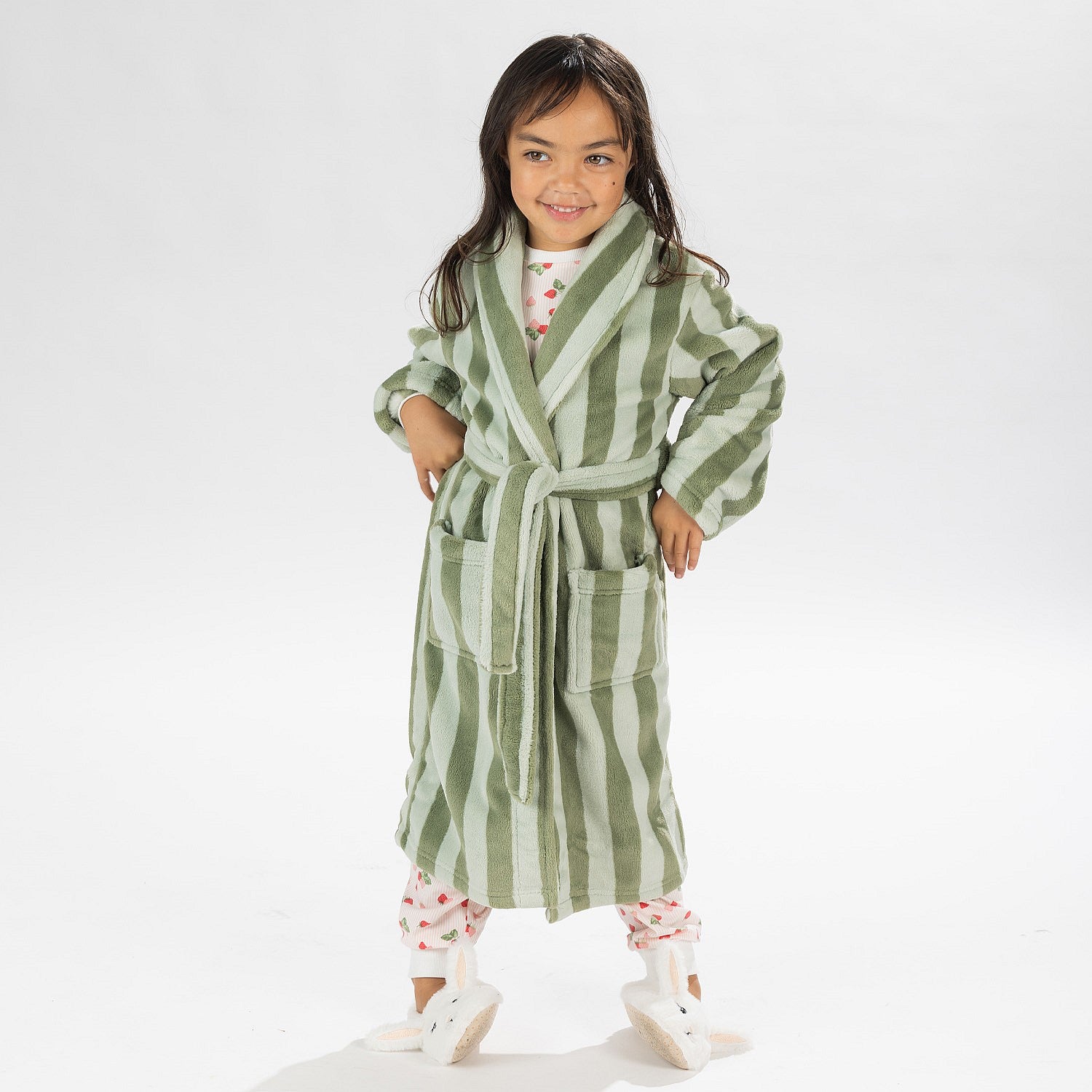 Child wearing a green striped robe standing on a white background.