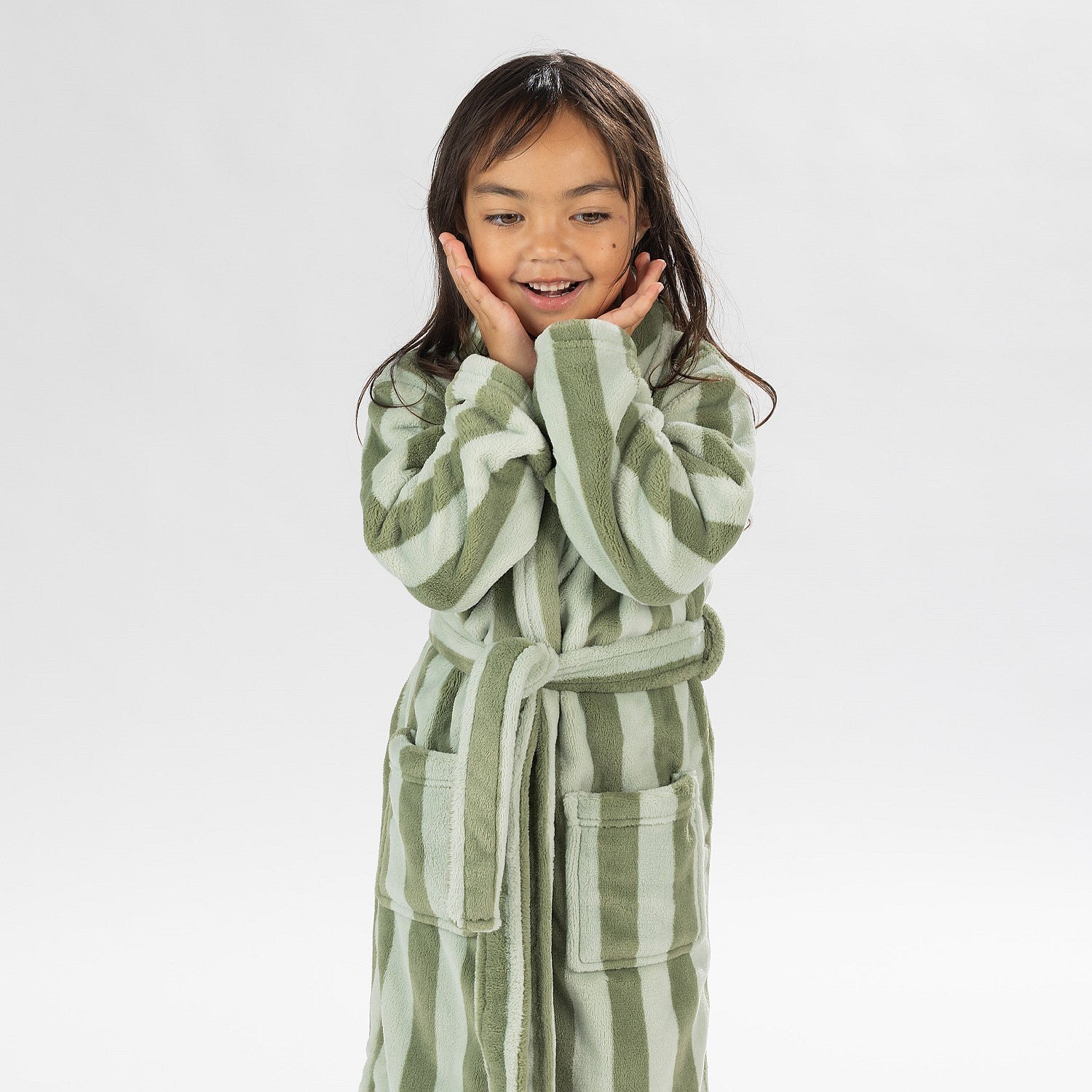 Child wearing a green striped robe standing on a white background.