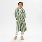 Child wearing a green striped robe standing on a white background.