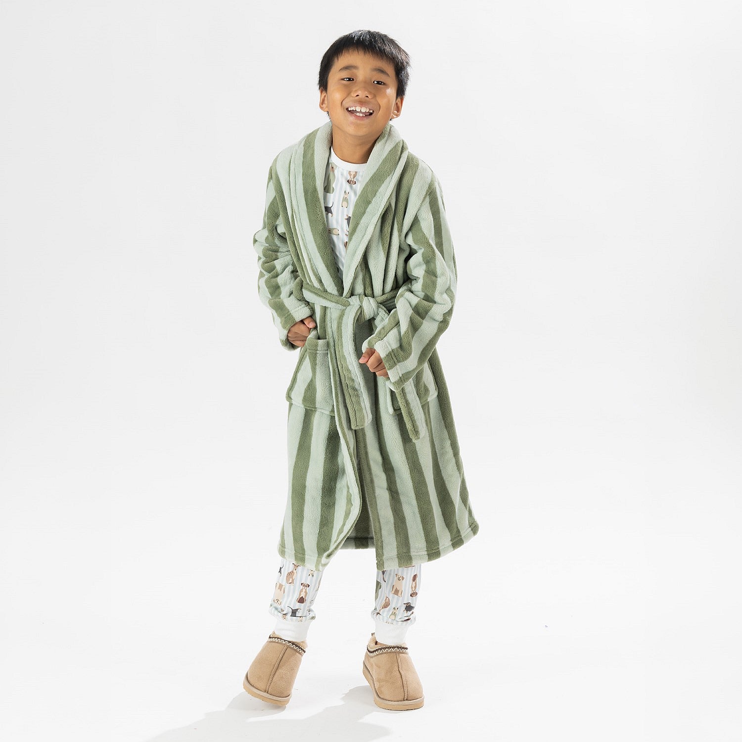 Child wearing a green striped robe standing on a white background.
