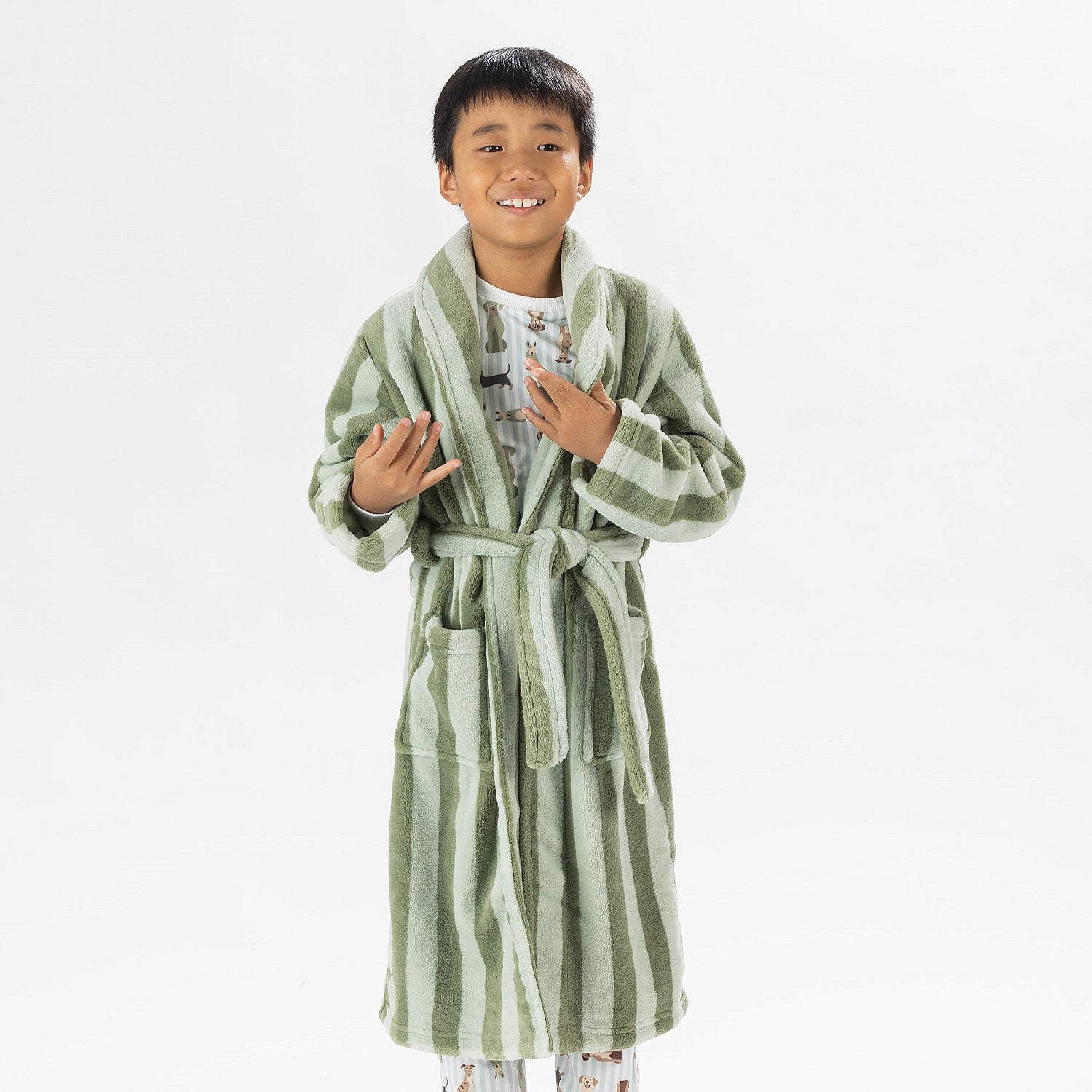 Child wearing a green striped robe standing on a white background.