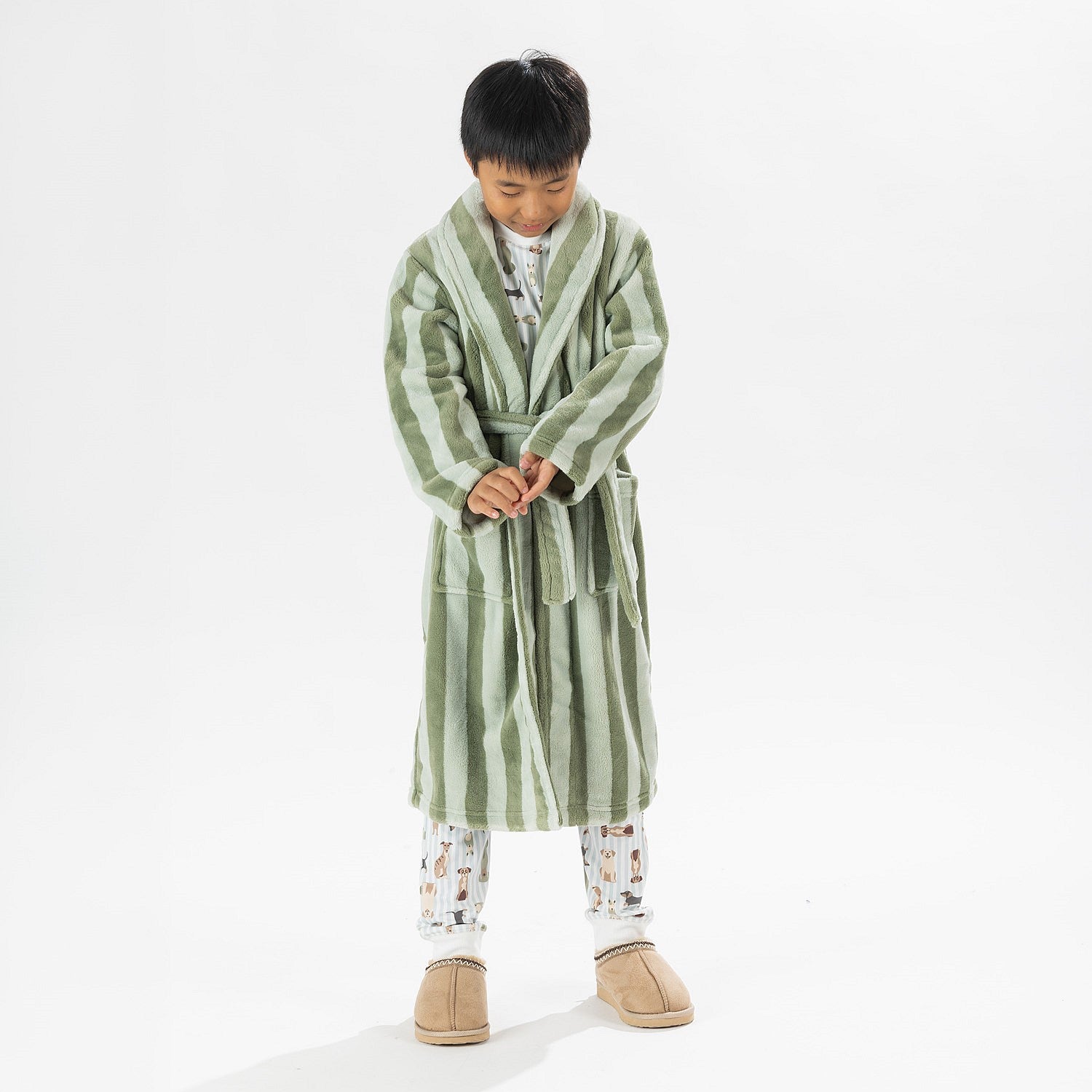 Child wearing a green striped robe standing on a white background.