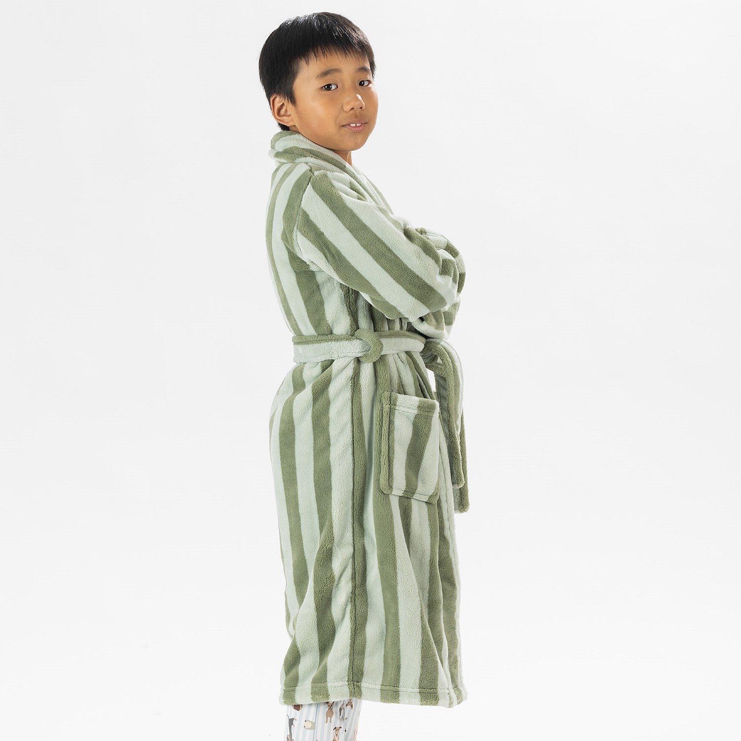 Child wearing a green striped robe standing on a white background.