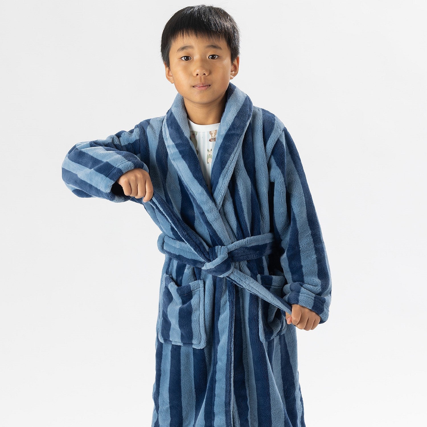 Child wearing a blue striped robe standing on a white background.