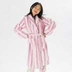 Child wearing a pink striped robe standing on a white background.