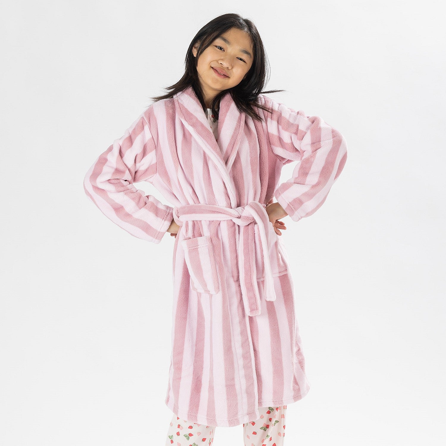 Child wearing a pink striped robe standing on a white background.