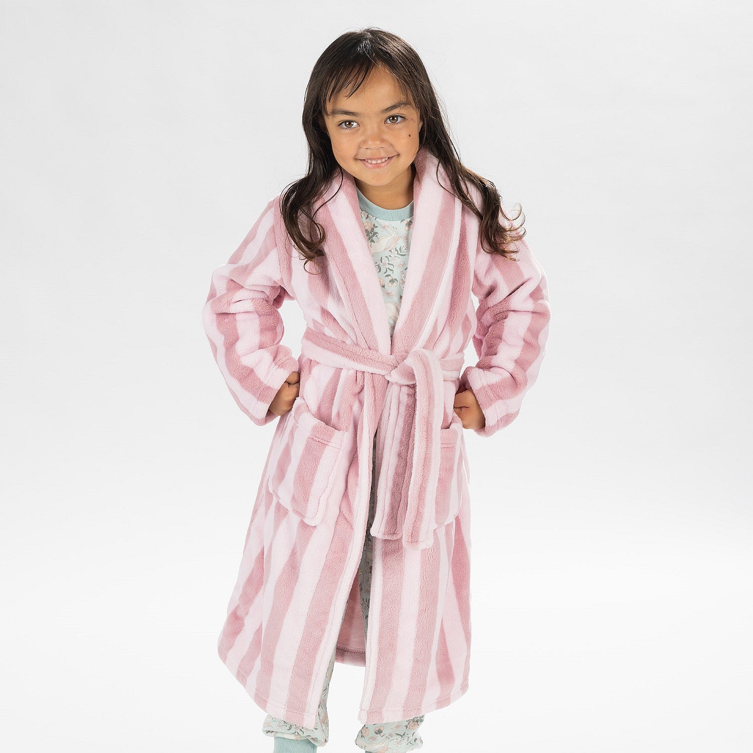 Child wearing a pink striped robe standing on a white background.