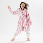 Child wearing a pink striped robe standing on a white background.