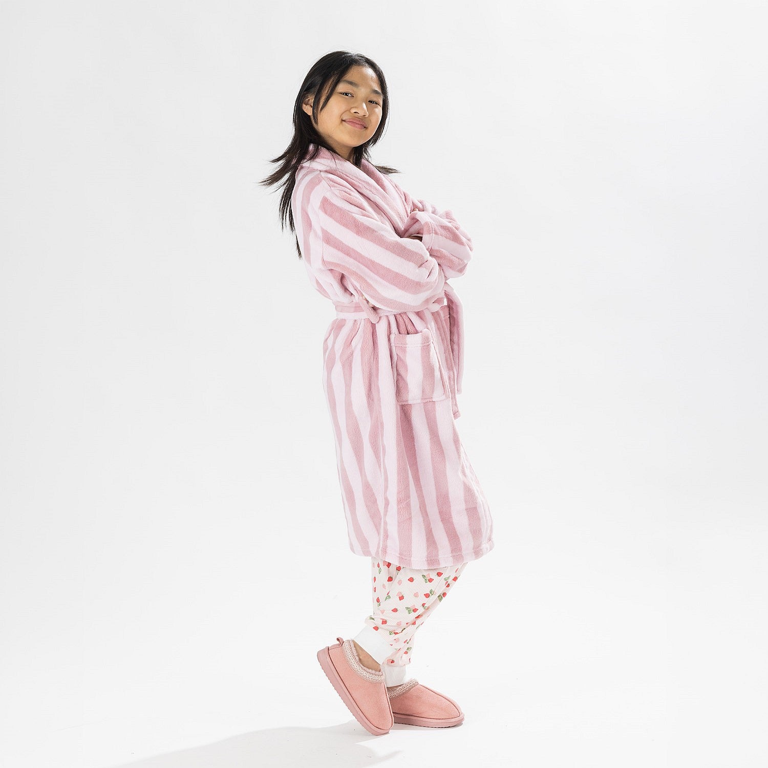 Child wearing a pink striped robe standing on a white background.