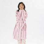Child wearing a pink striped robe standing on a white background.