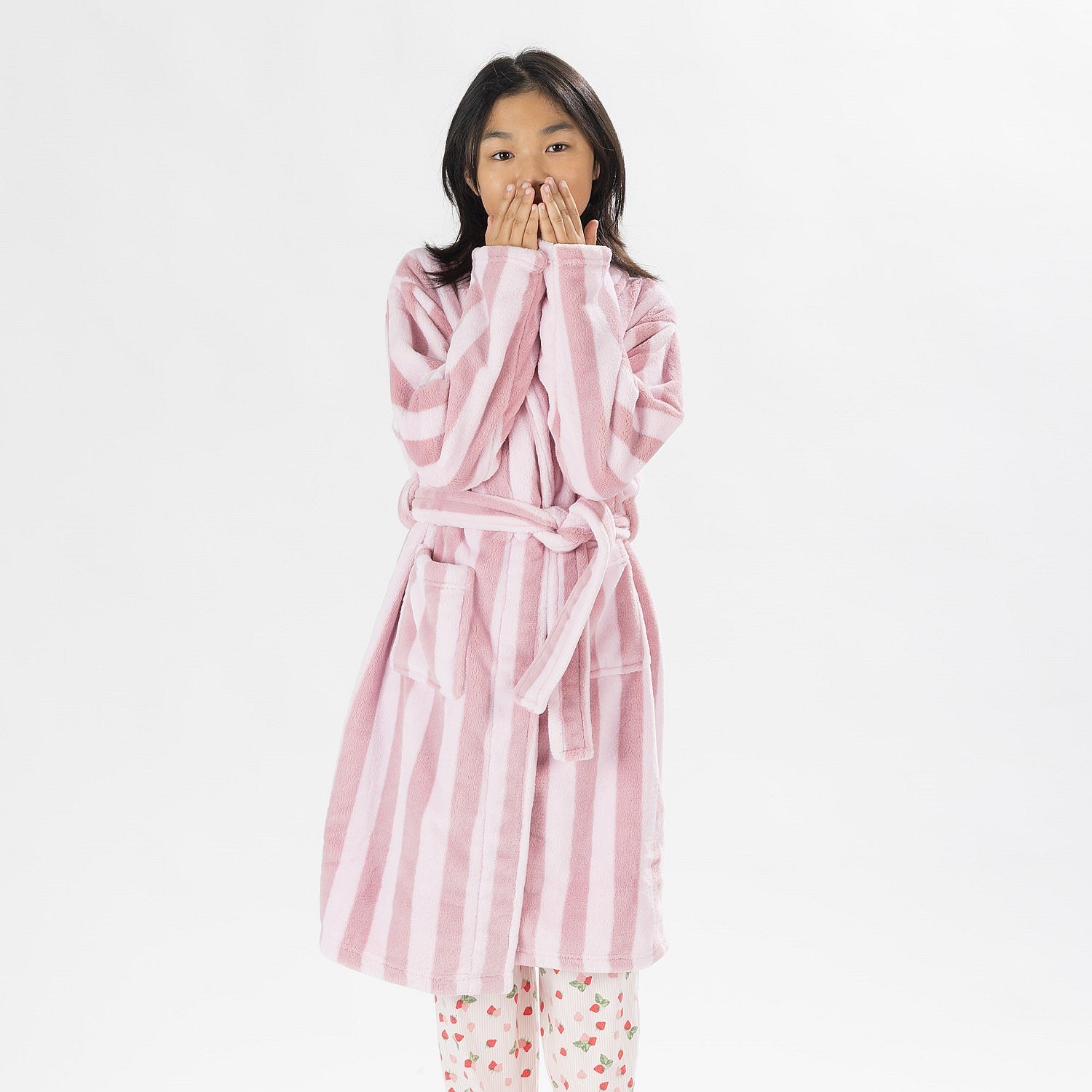 Child wearing a pink striped robe standing on a white background.