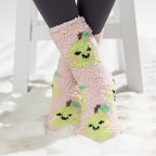 Pink kids bed socks with green pear design, worn on a soft white rug.
