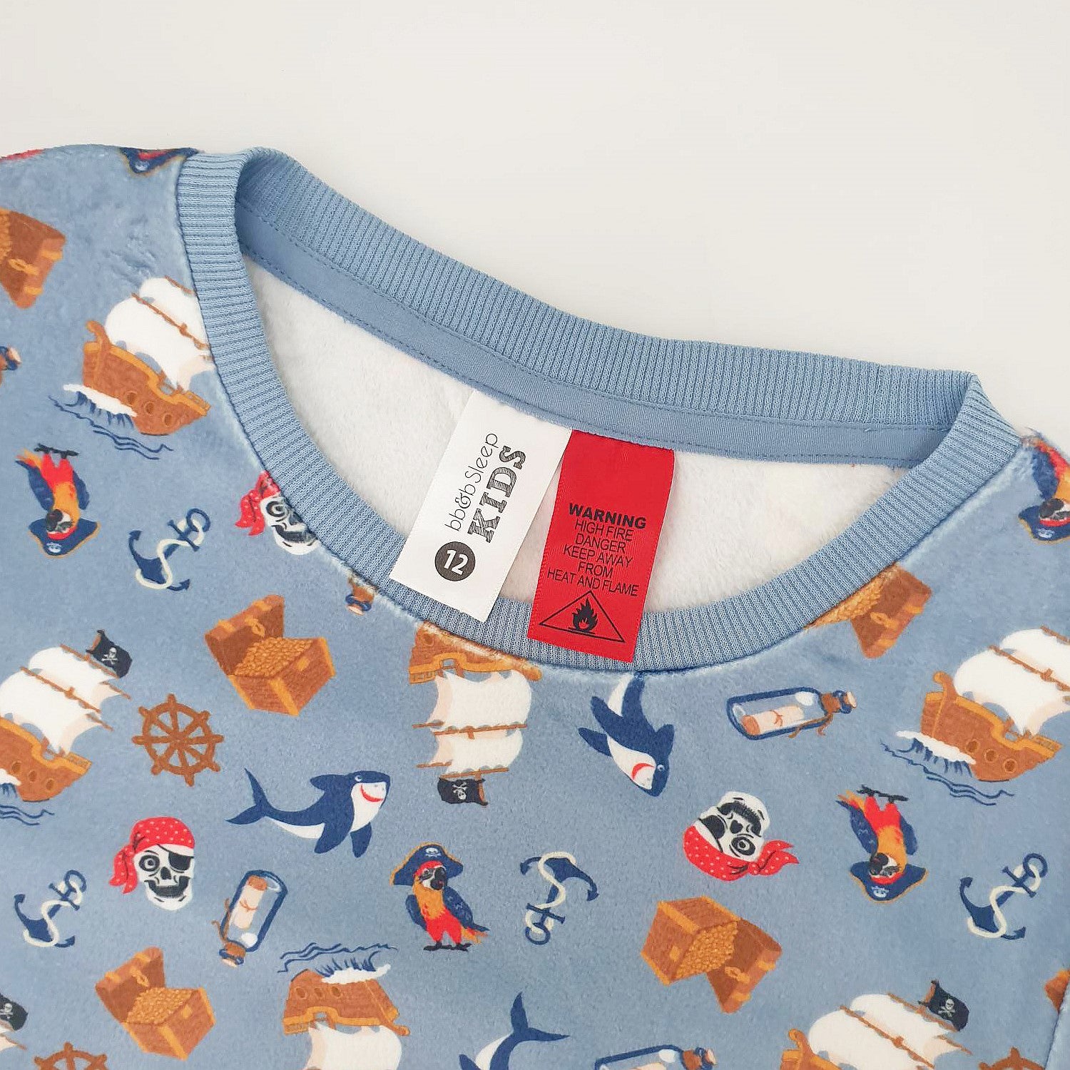 close up of blue pirate printed pyjamas showing the warning label and tag.