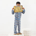 Child wearing blue pirate printed pyjamas standing on a stool on a white rug.