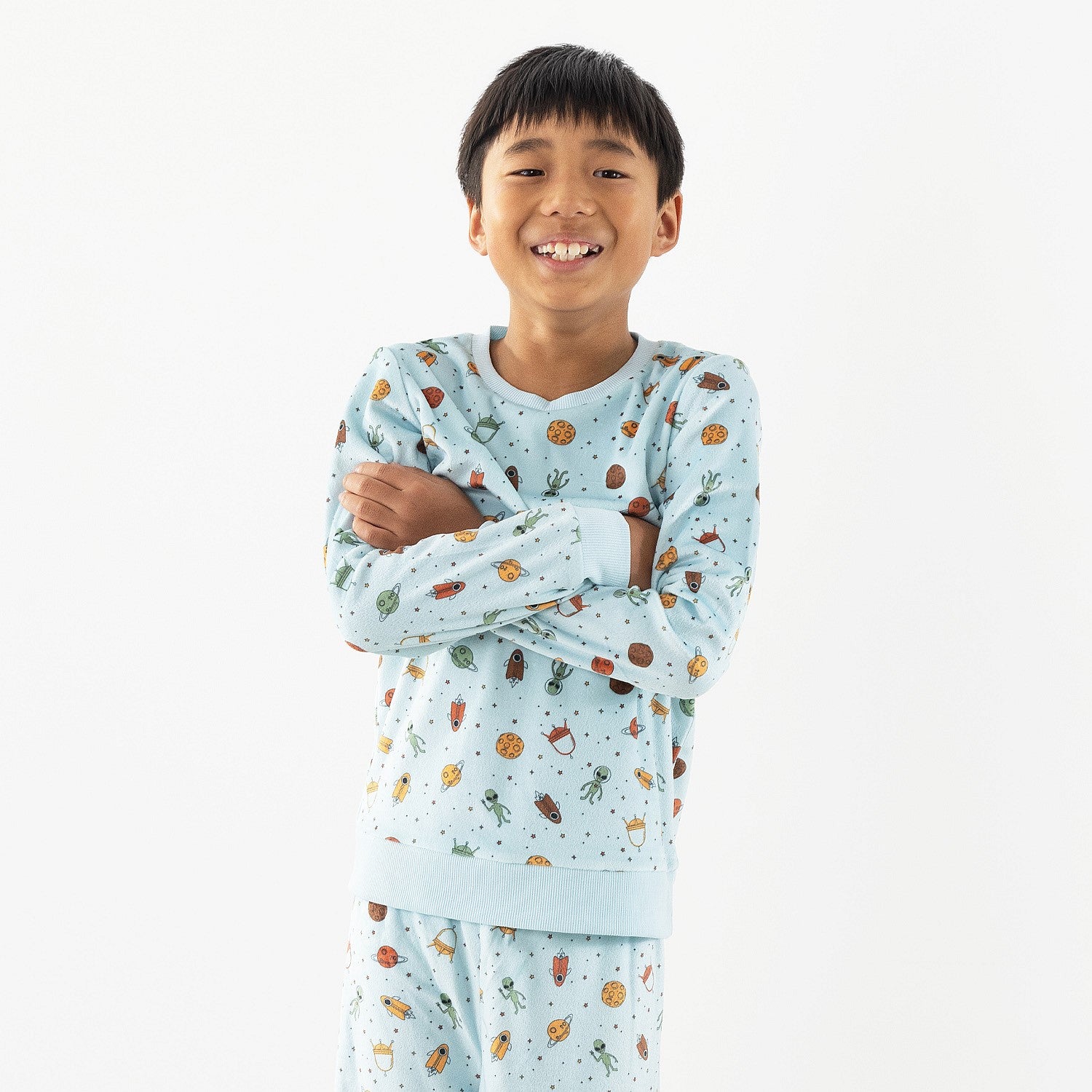 Child wearing light blue space printed pyjamas on a white background.